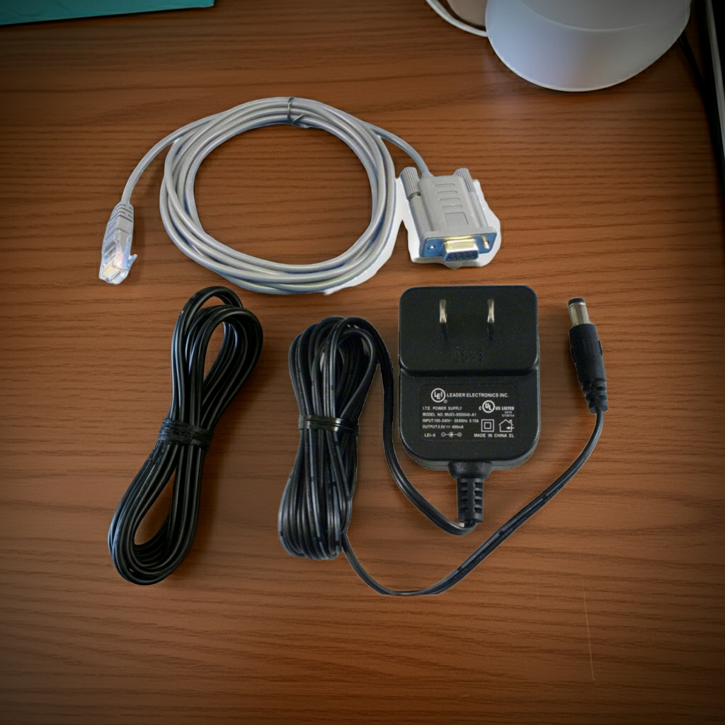 DB9 serial kit with gray cable, black cords, and power adapter